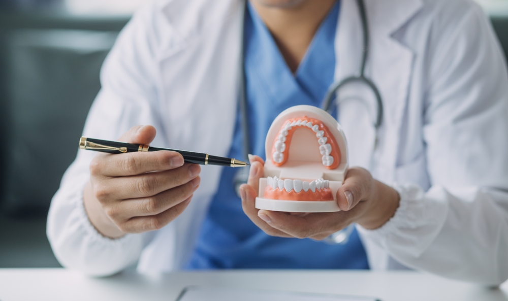 doctor showing a set of teeth with a fountain pen